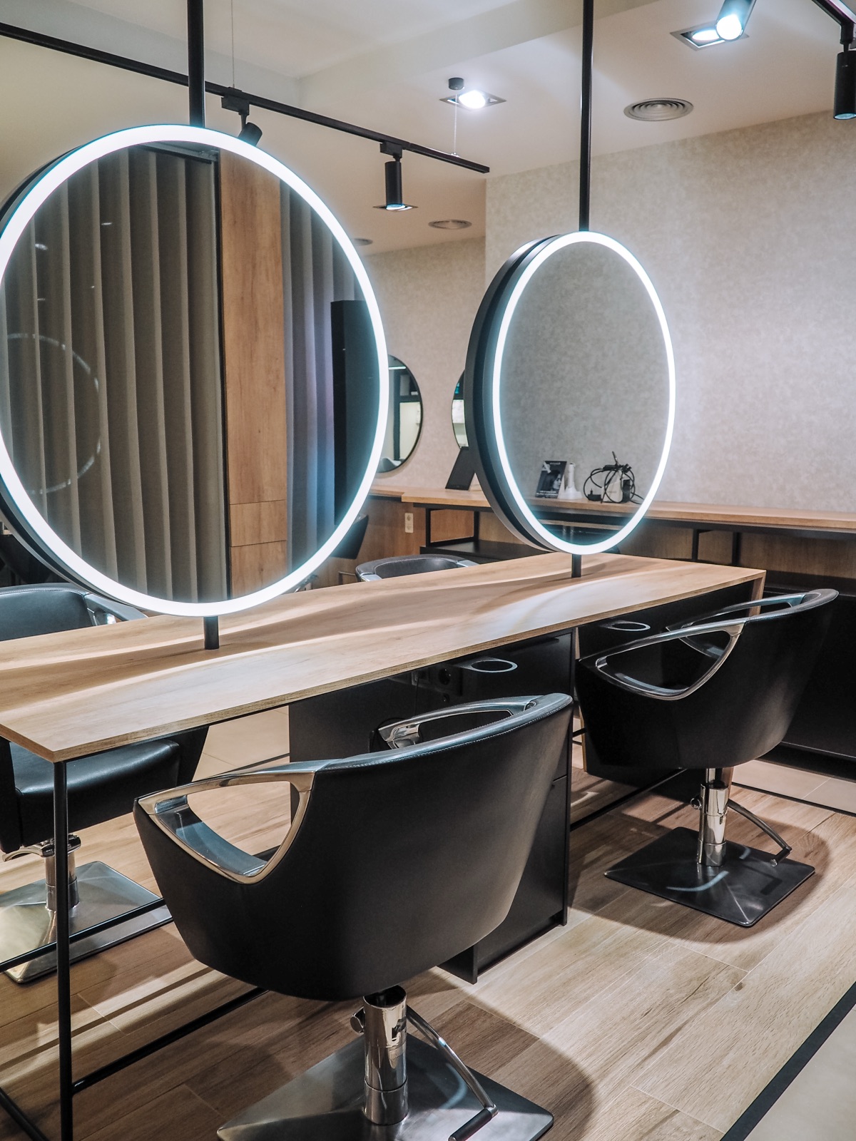 Interior do salão Isabel Boaventura Cabeleireiros no Porto, com espelhos circulares LED e estações de styling